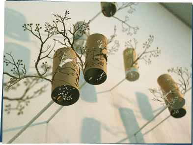 Toilet paper rolls with tree shapes cut out, hanging on the wall.