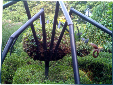 A spider topiary with long black pipes for legs