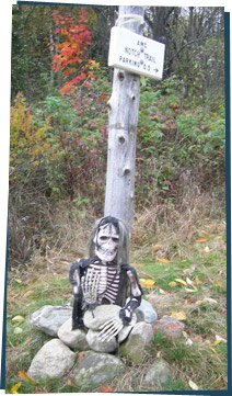 Rubber skeleton at a signpost on a trail