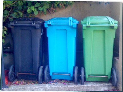 Three trash bins: black, blue, and green