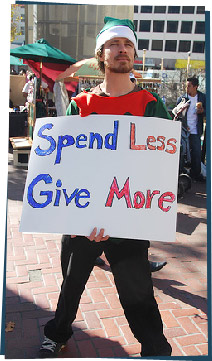 A man holding a sign that says "Spend Less, Give More"